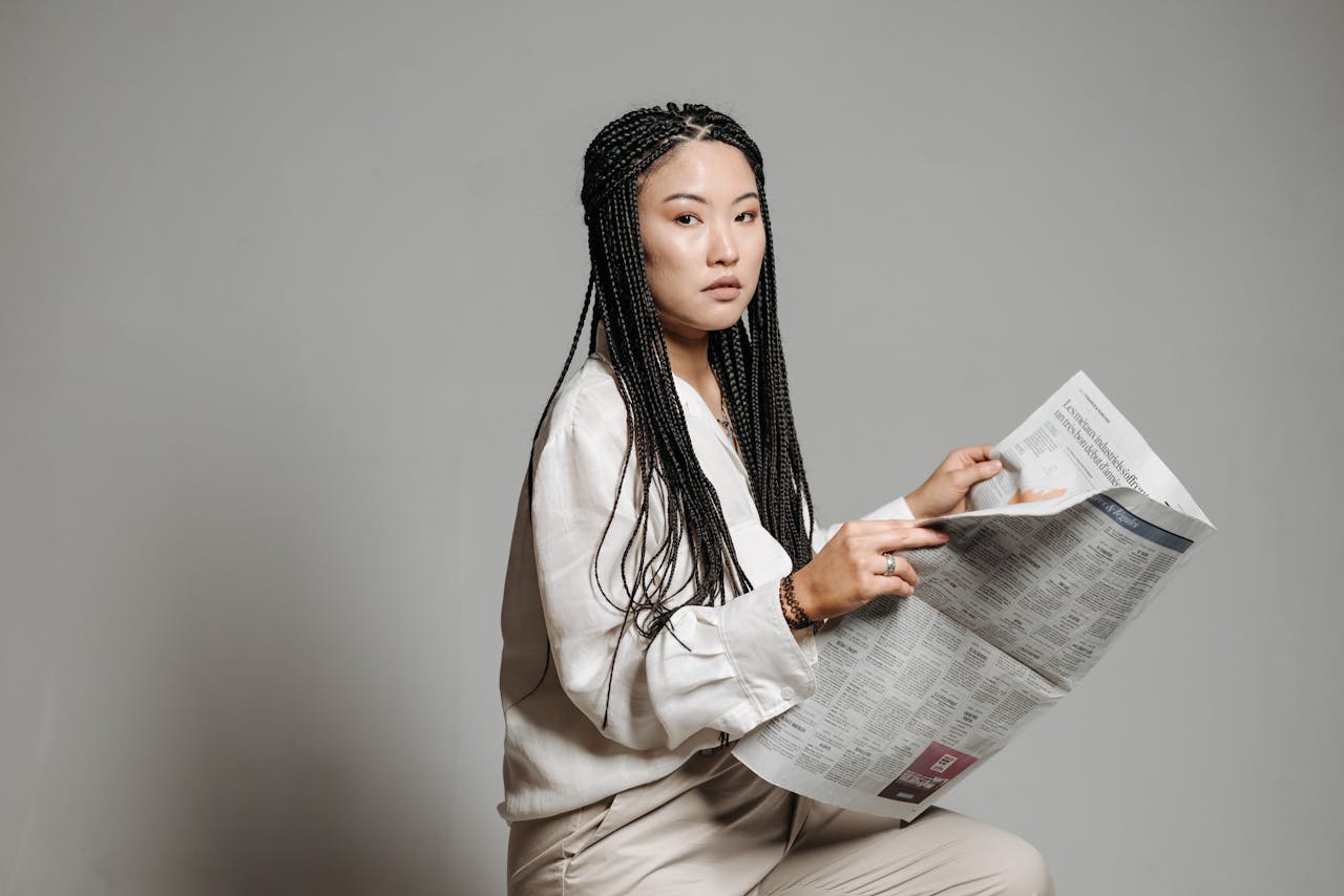 A Woman in a Button Down Shirt Holding a Newspaper